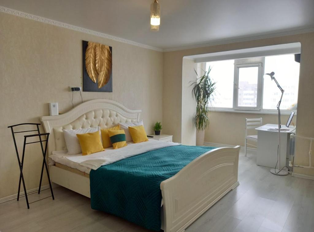 une chambre avec un grand lit avec des draps jaunes et bleus dans l'établissement Космос-Лайт, à Aqtöbe