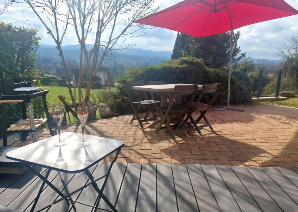a patio with a table and a red umbrella at Gîte de France La petite marmotte in Saint-Béron