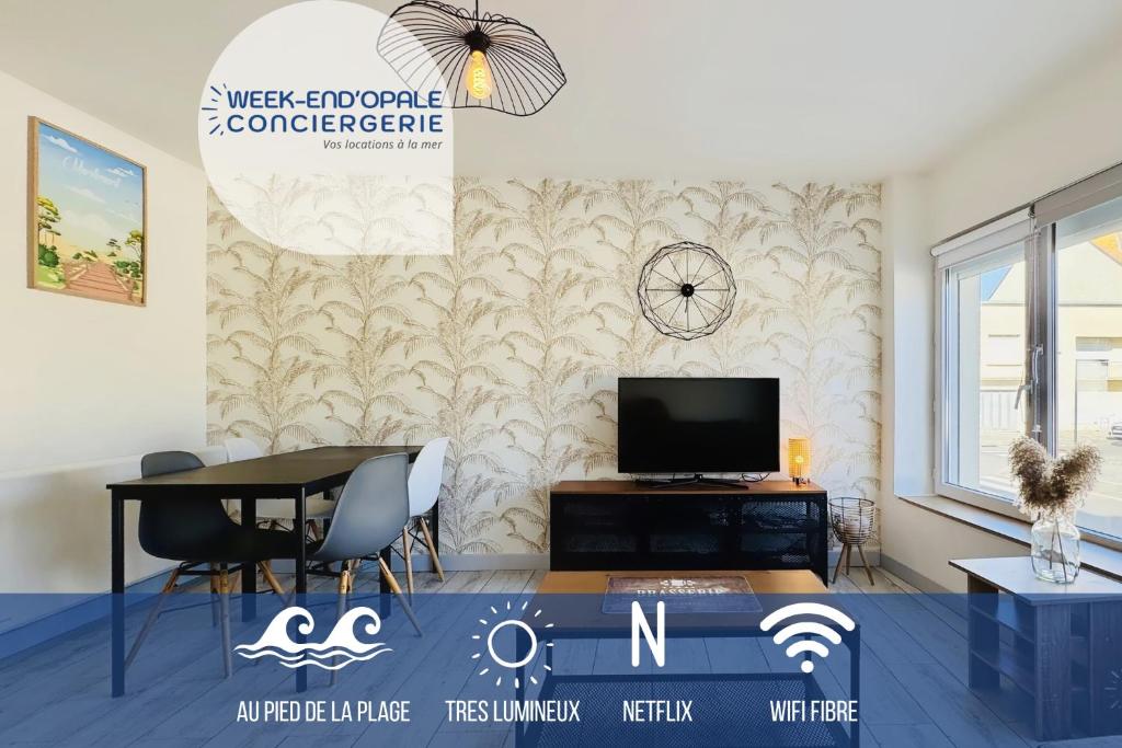 a living room with a table and a tv on a wall at Appartement Sunrise au pied de la plage in Merlimont