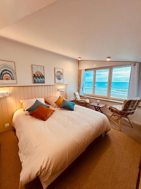 une chambre avec un grand lit et une grande fenêtre dans l'établissement L'écume de mer, à Barneville-Carteret