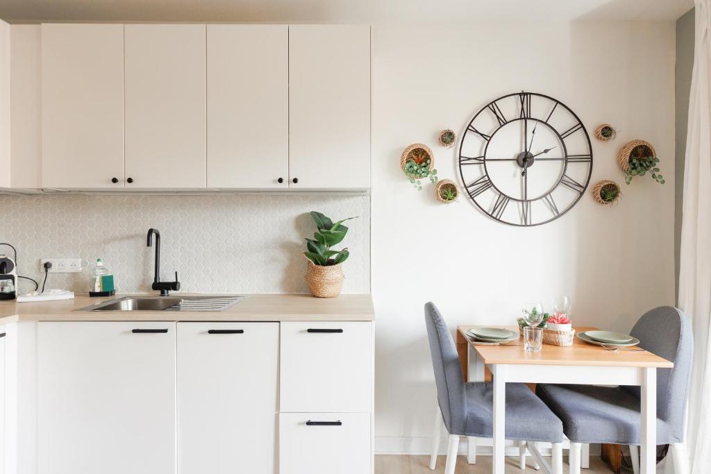 une cuisine avec des placards blancs et une table avec une horloge murale dans l'établissement Immogroom - Warm T2 - AC - Wifi - Comfort, à Cannes