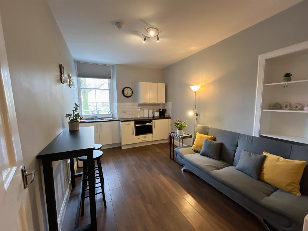 a living room with a blue couch and a kitchen at Comfortable one-bedroom apartment Free parking space in Edinburgh