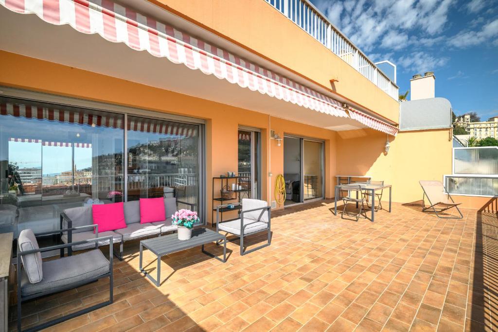 un patio avec des chaises et des tables sur un bâtiment dans l'établissement 'L'Alicante proche' gare, terrasse, vue mer, à Menton