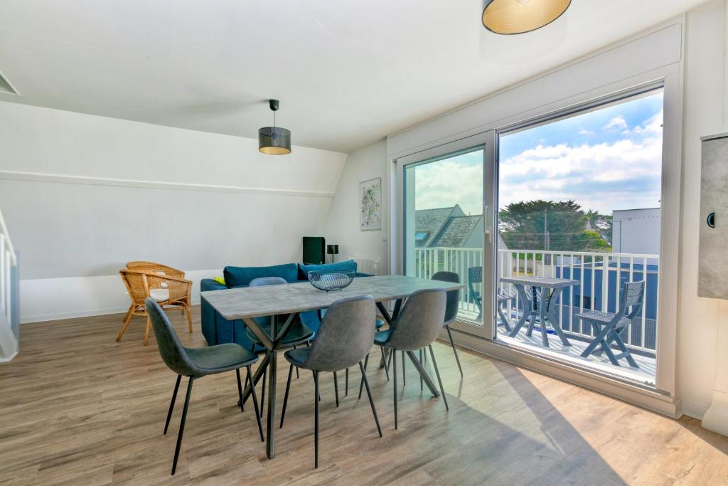 une salle à manger avec une table et des chaises et une grande fenêtre dans l'établissement Bel appartement - 2min plage, à La Turballe