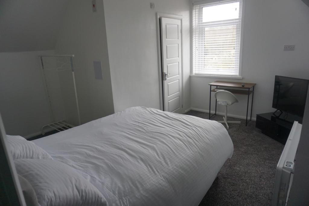 a bedroom with a bed and a desk and a television at Horsforth Rooms by LBA in Horsforth