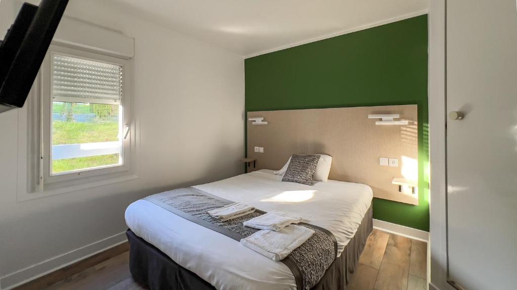 a bedroom with a bed with a green accent wall at Fasthotel Le Mans Nord FH CONFORT in Saint-Saturnin
