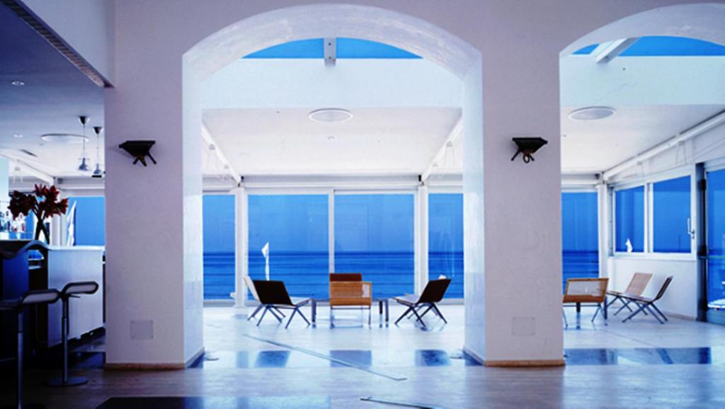 een kamer met een tafel en stoelen en de oceaan bij Hotel Amyclae in Sperlonga