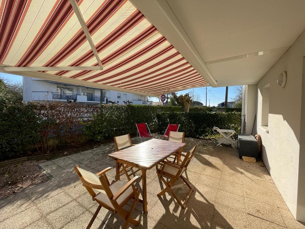 a patio with a wooden table and chairs under awning at Superbe appartement très spacieux en centre ville in Capbreton