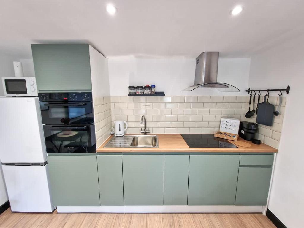 a kitchen with a sink and a white refrigerator at Kirkby Bungalow by City SuperHost in Kirkby
