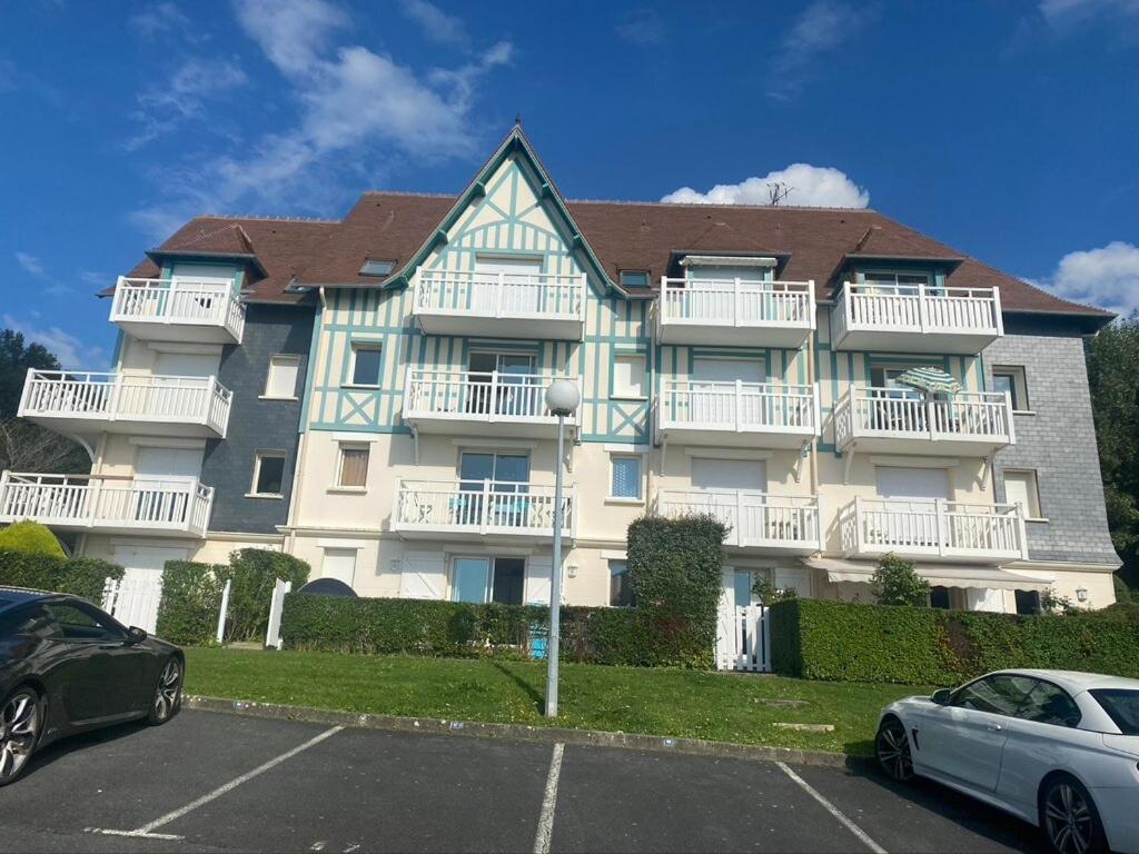 un grand immeuble avec des voitures garées dans un parking dans l'établissement Beautiful F3, sea view, panoramic, à Blonville-sur-Mer