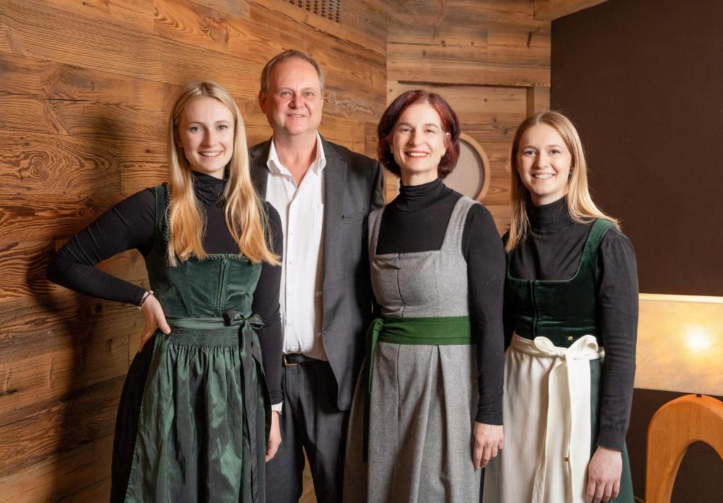 a man and four women standing next to a wall at Hotel Der Löwe LEBE FREI in Leogang