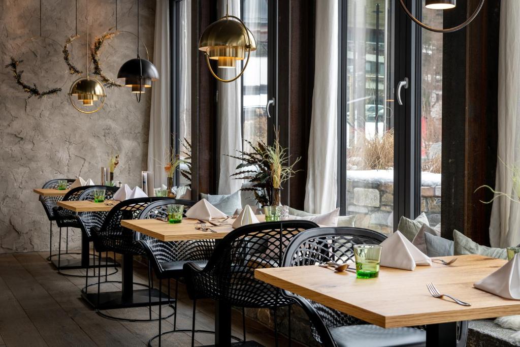 a restaurant with wooden tables and chairs and a window at Hotel Der Löwe LEBE FREI in Leogang