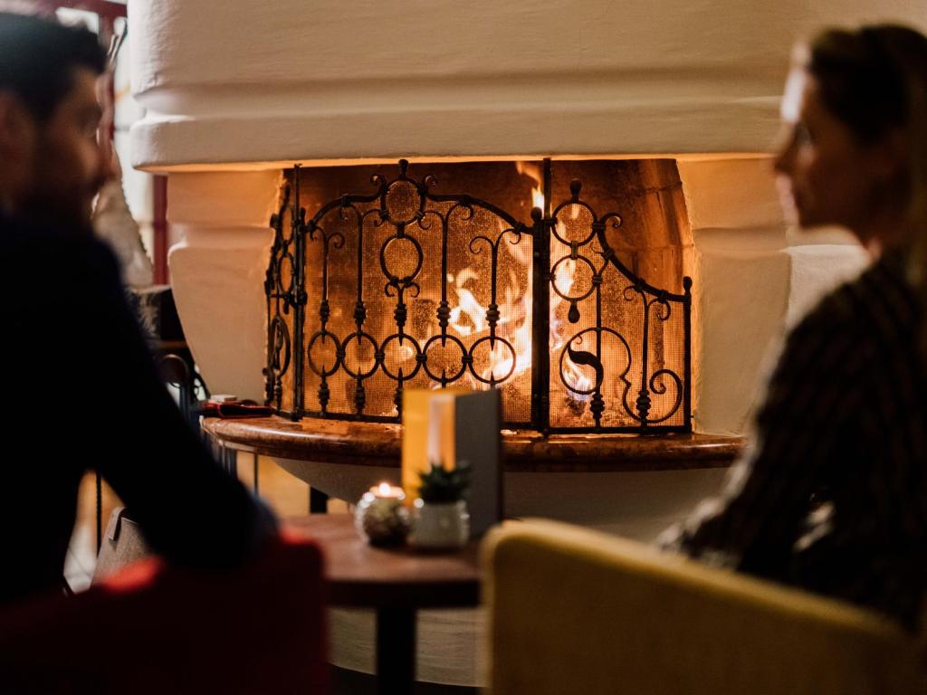 a woman sitting at a table in front of a fireplace at Hotel Der Löwe LEBE FREI in Leogang