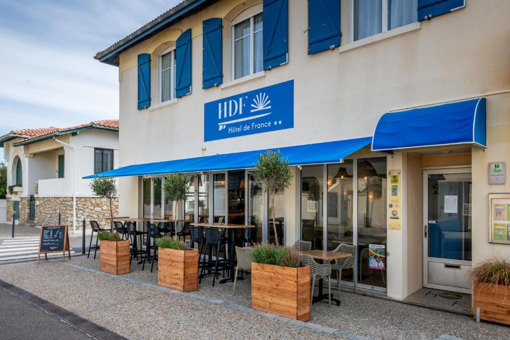 a restaurant with tables and chairs in front of a building at Logis Hotel de France in Mimizan-Plage