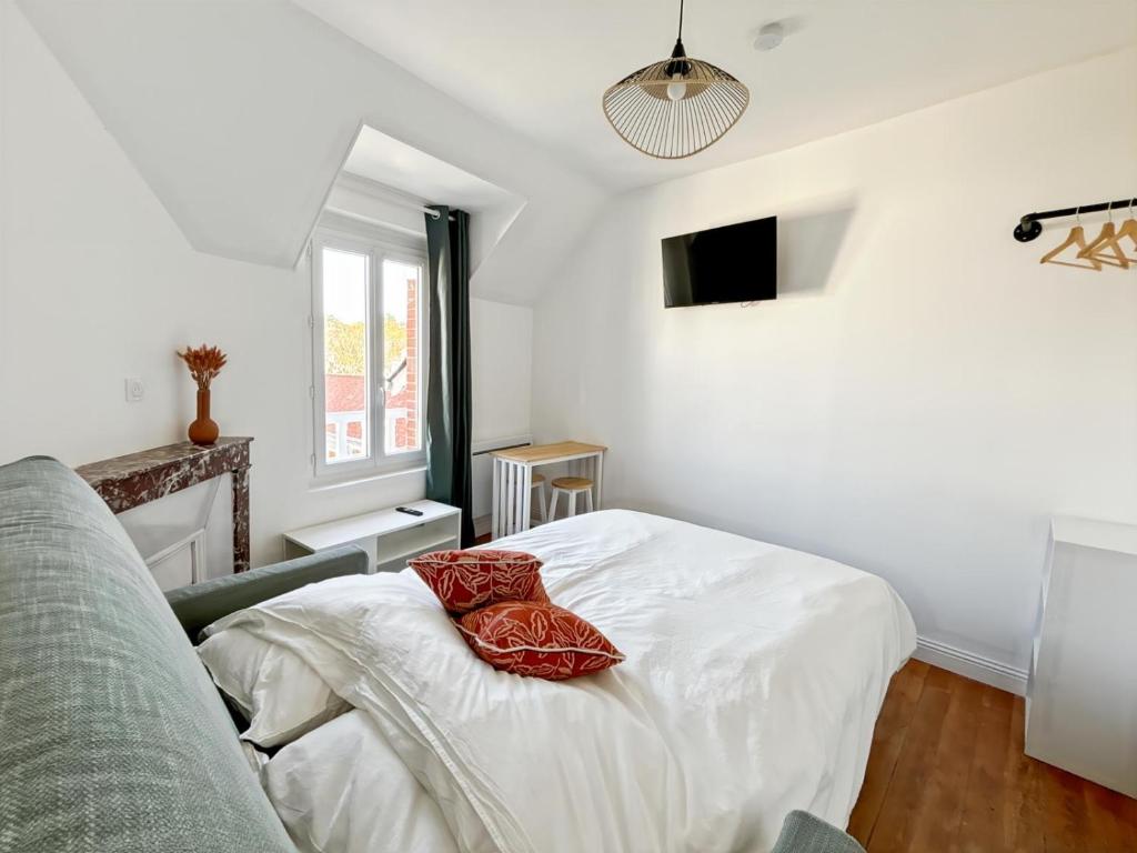 une chambre avec un lit avec deux oreillers rouges dessus dans l'établissement Studio Symphonie des Mers, à Criel-sur-Mer