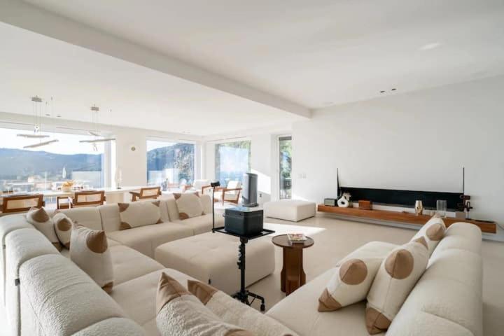 Il comprend un salon doté d'un mobilier blanc et d'une télévision à écran plat. dans l'établissement Villa de luxe avec vue panoramique sur la mer et Monaco, à Roquebrune-Cap-Martin