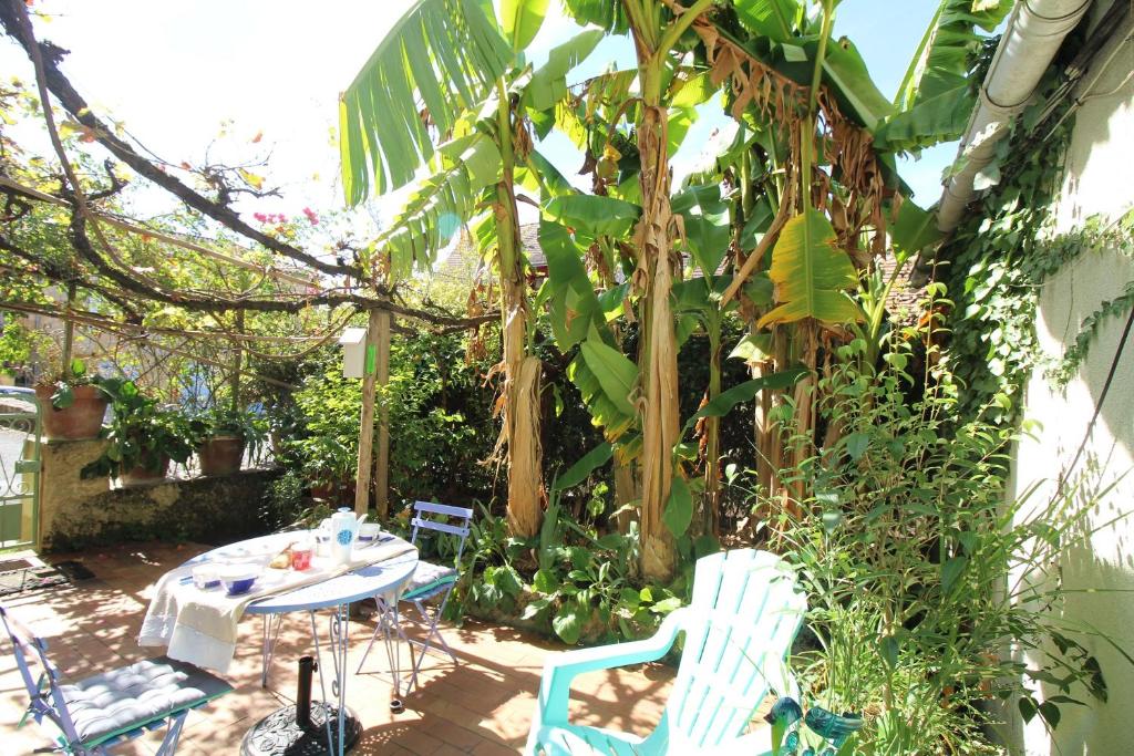 a patio with a table and chairs in a garden at le gîte de Claire maison avec terrasse, calme et confort, lit king size linge fourni in Couze-et-Saint-Front
