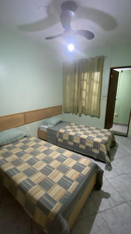 two beds in a room with a ceiling fan at Hospedagem Belo Horizonte in Macaé