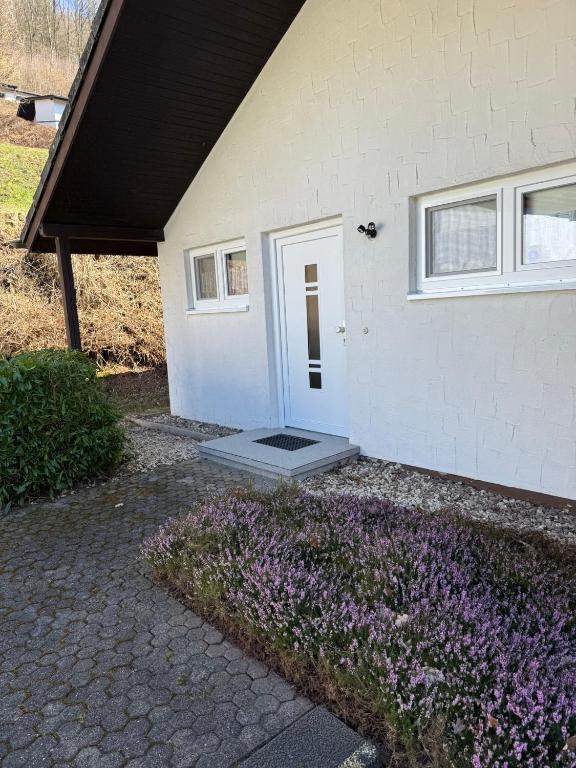 a white house with purple flowers in front of it at Ferienhaus Stausee Bitburg in Biersdorf am See