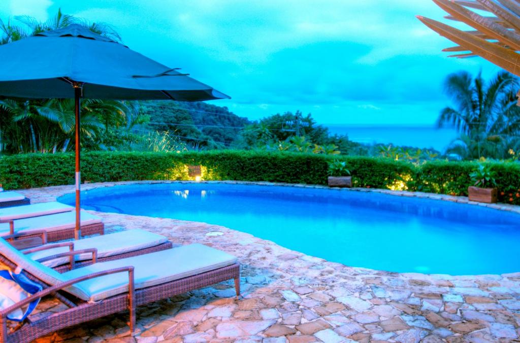 a swimming pool with two lounge chairs and an umbrella at Casa Chameleon Hotel Mal Pais - Adults Only in Santa Teresa Beach