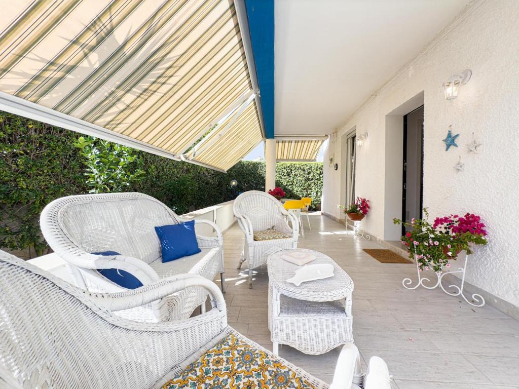 a patio with white wicker chairs and tables at Villa Leandra in Fontane Bianche