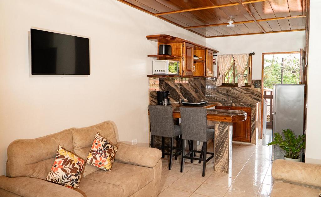 a living room with a couch and a kitchen with a bar at Departamento Ángeles del Arenal #2 in Fortuna