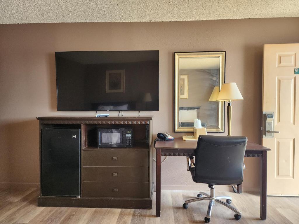 a room with a desk and a television and a chair at Satellite Inn in Alamogordo