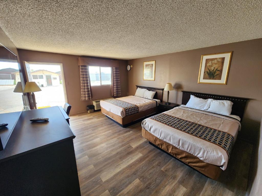 a hotel room with two beds and a desk at Satellite Inn in Alamogordo