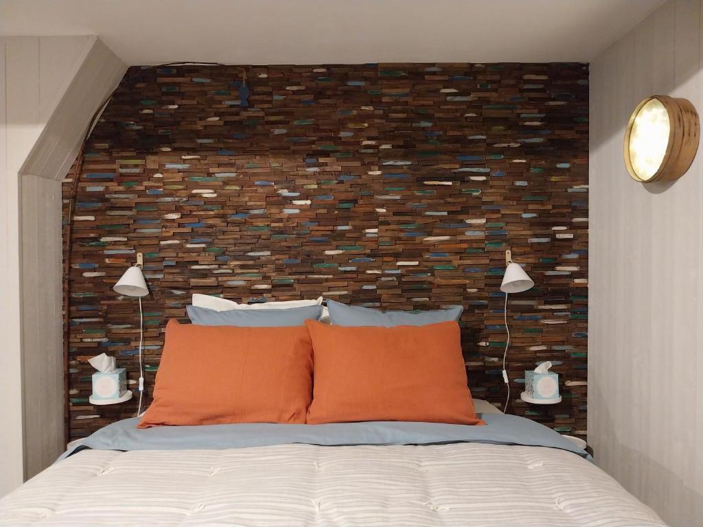 een slaapkamer met een bakstenen muur achter een bed bij La petite cabane du pecheur in Honfleur