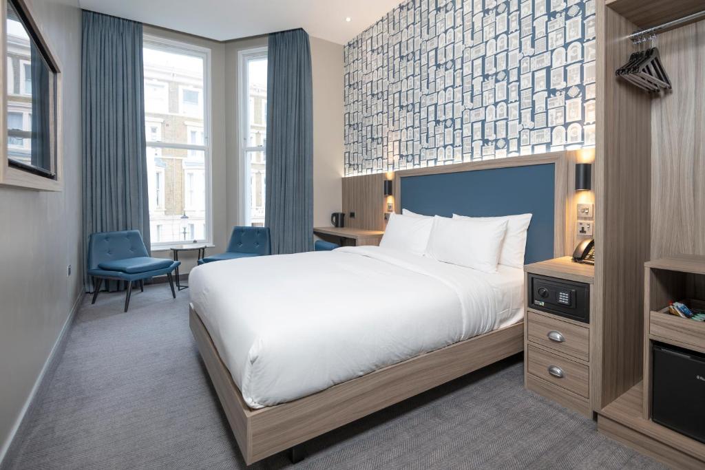 a hotel room with a bed and a desk and chair at Brit Hotels Earls Court in London