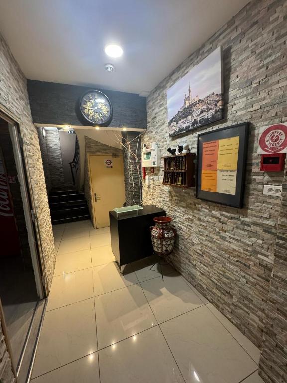 un couloir avec une horloge sur un mur de briques dans l'établissement Faculte Hotel, à Marseille
