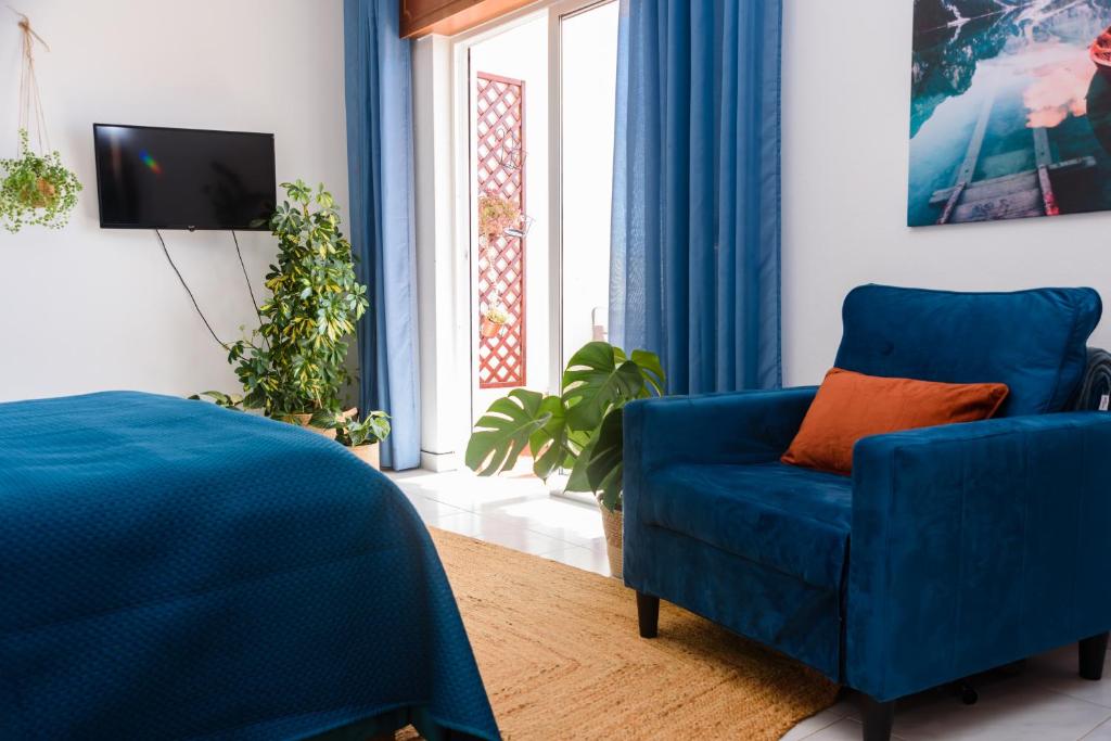 a living room with a blue chair and a tv at Hillside Studio with Sea View & Fibre Internet in Albufeira