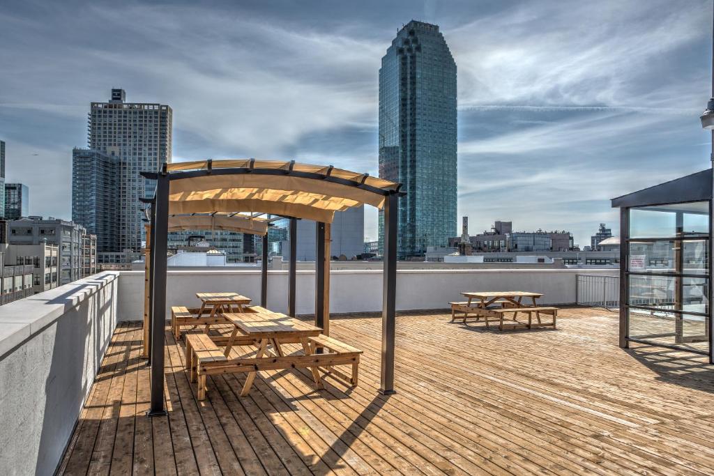 a row of wooden picnic tables with umbrellas at LIC Hotel in Queens