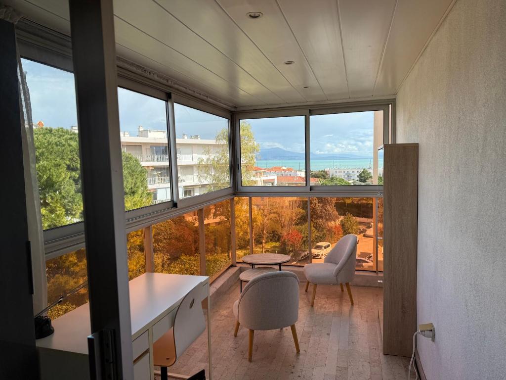 Cette chambre dispose de grandes fenêtres, d'une table et de chaises. dans l'établissement Dernier étage vue mer avec parking et piscine, à Antibes