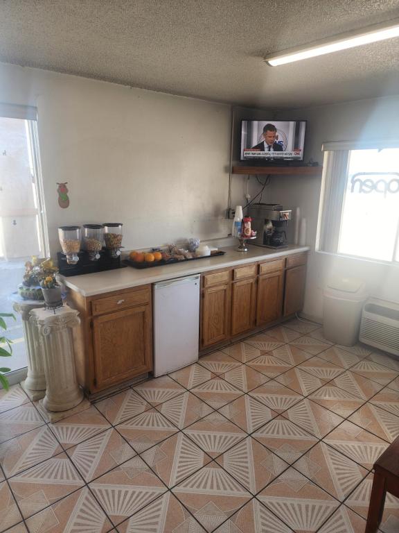 a kitchen with wooden cabinets and a tv on the wall at Satellite Inn in Alamogordo