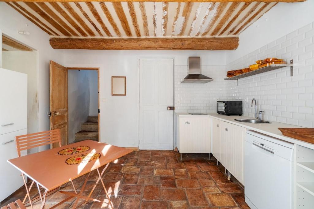 une cuisine avec des armoires blanches et un plafond en bois dans l'établissement gîtes carita, à Cabannes