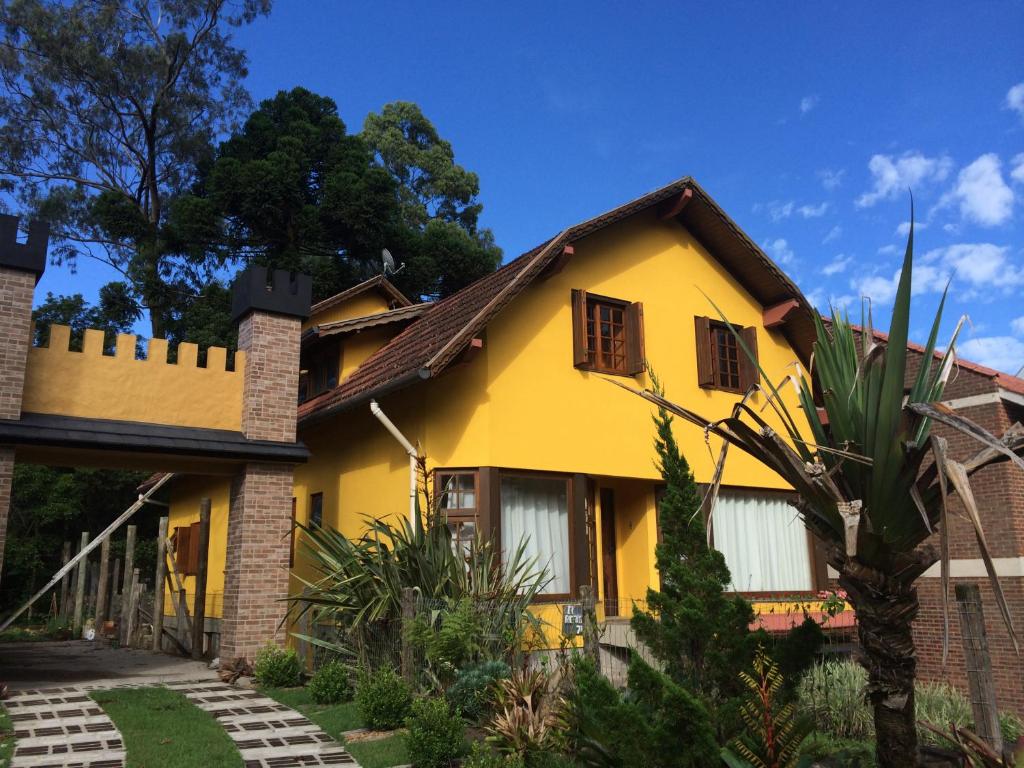 una casa amarilla con techo marrón en El Refugio 700, en Gramado