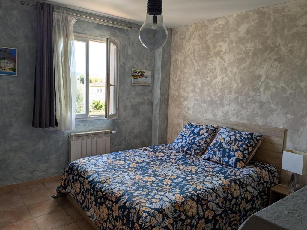 Un dormitorio con una cama con edredón azul y una ventana. en Entre plage et vignobles Maison trois chambres, en Saint-Cyr-sur-Mer