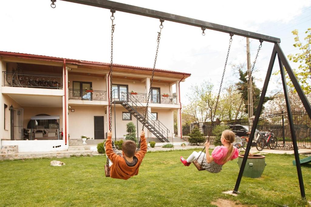 two children playing on a swing set in a yard at Casa Haralambie in Greci