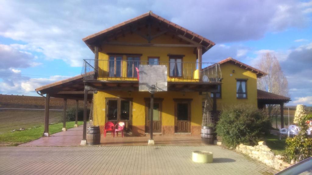 Una casa amarilla con balcón en la parte superior. en Casarural Vallecillo, en Vallecillo