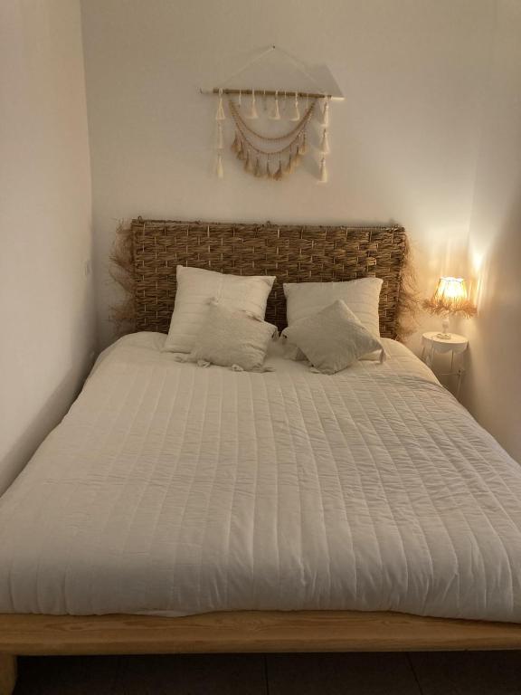 Elle comprend un grand lit avec des draps et des oreillers blancs. dans l'établissement Appartement cosy centre du Crès, à Le Crès