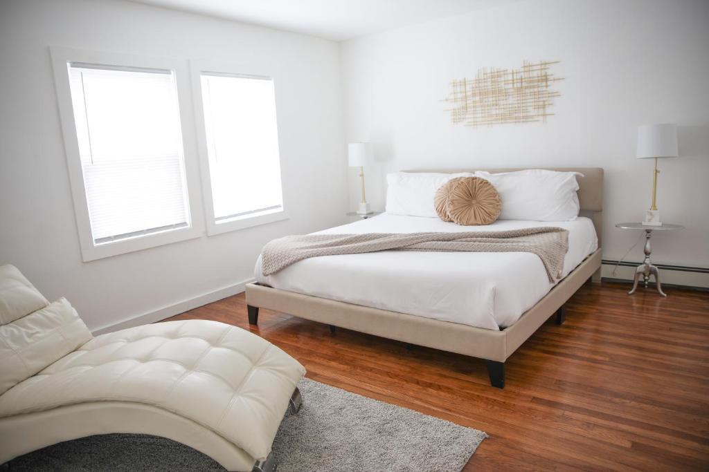 a white bedroom with a bed and a chair at Cozy Near Boston with Outdoor Space in Everett