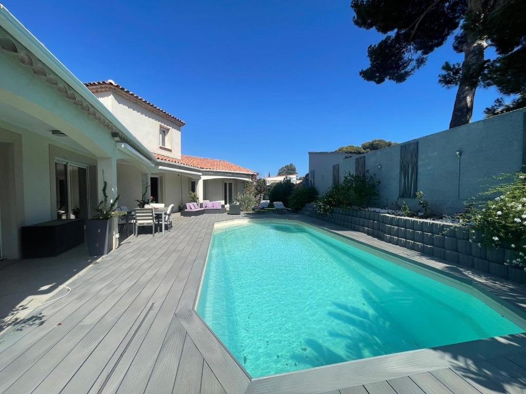 une maison avec une piscine et une terrasse en bois dans l'établissement Villa avec piscin, proche plages et centre, à Sausset-les-Pins