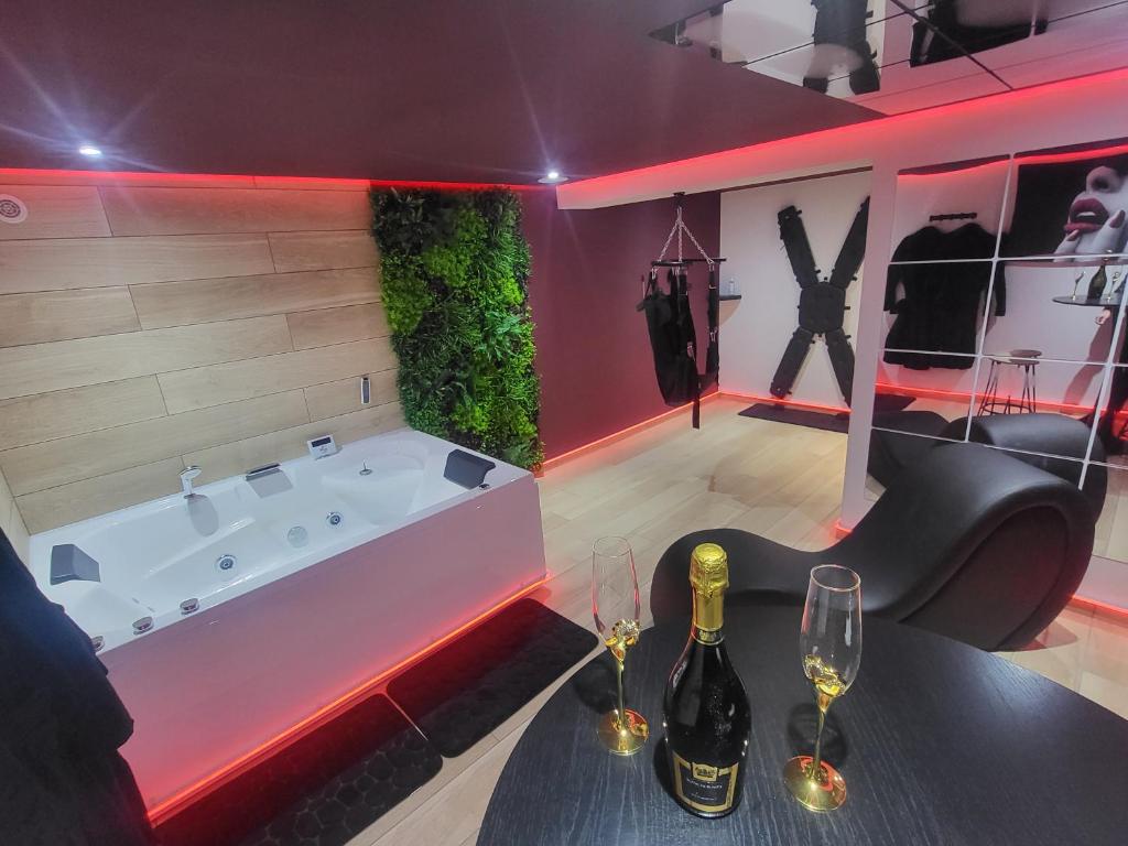une chambre avec une baignoire et deux verres à vin dans l'établissement L'incontournable Love Room, à Peyrins