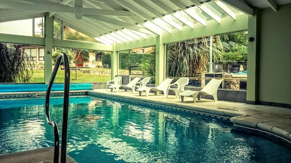 una piscina con sillas blancas y una piscina en Samai Suma Cabañas & Spa en Villa General Belgrano