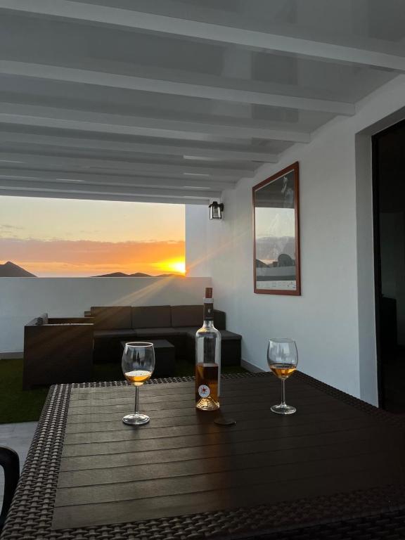 two glasses of wine sitting on a wooden table with the sunset at Casa Picacho in Tinajo