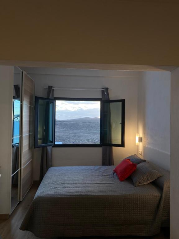 a bedroom with a large bed with a large window at Casa Picacho in Tinajo