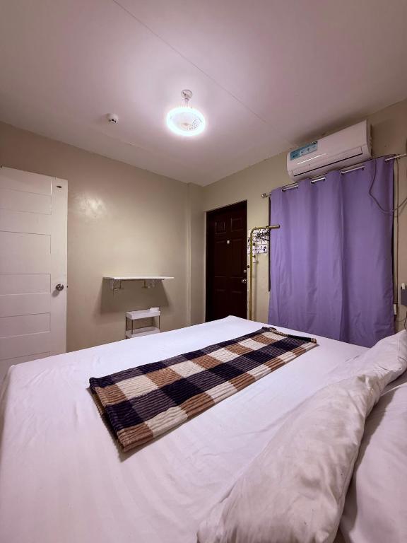 a bedroom with a large white bed with purple curtains at Dau homesite mabalacat pampanga in Mabalacat