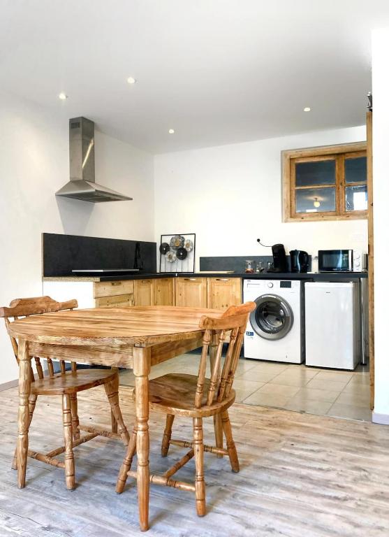 une cuisine avec une table et des chaises en bois dans l'établissement Résidence Pifourcha La Roche Entre Sisteron & Serre-Ponçon, à Le Caire