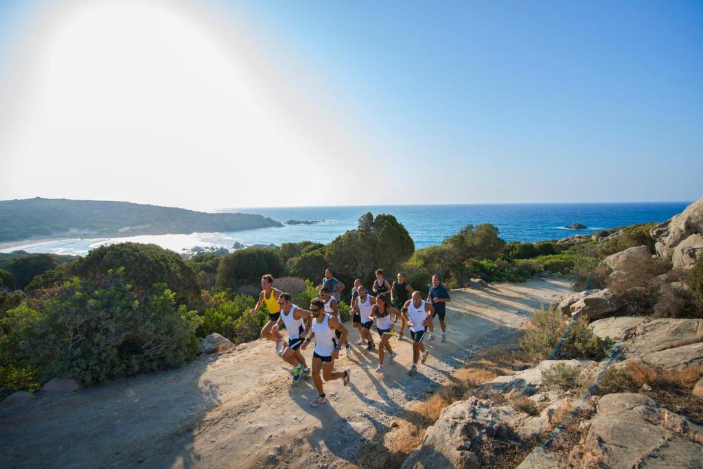 a group of people running on a trail near the ocean at Chia Laguna - Hotel Village in Chia